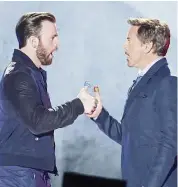  ??  ?? Boys will be boys. Evans ( left) and Downey Jr play thumb war.