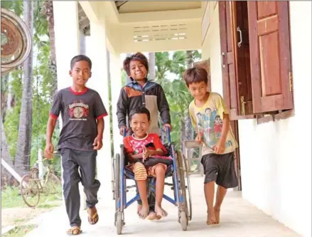  ?? UN CAMBODIA ?? Children help their peer with disabiliti­es.