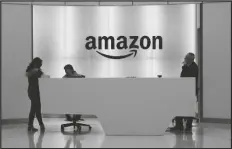  ?? ASSOCIATED PRESS FILE PHOTO ?? PEOPLE STAND IN THE LOBBY OF AMAZON’S OFFICES in New York in February 2019. While other companies are shrinking, Amazon is growing. The company said Wednesday that it is seeking to hire 33,000 people for corporate and tech roles in the next few months.