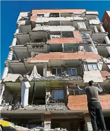  ??  ?? Helpless: A man reacting as he looks up at a damaged building. — Reuters