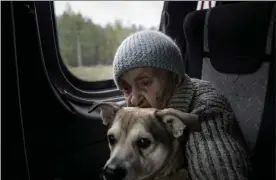  ?? AP ?? An elderly woman sits on a bus with her dog during evacuation from Lyman, in the Donetsk region of eastern Ukraine, on Saturday.