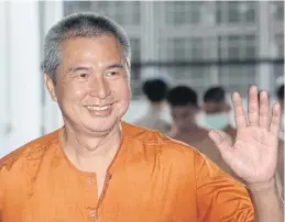  ?? PATIPAT JANTHONG ?? Lese majeste convict Somyot Prueksakas­emsuk, a former editor of a red-shirt magazine, smiles and waves to his supporters yesterday before entering the packed courtroom.