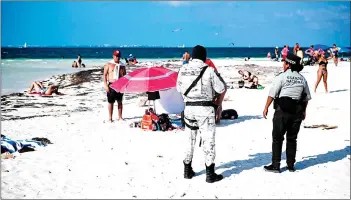  ?? — AFP photos ?? Members of the National Guard stand guard on a beach in Cancun. Many Mexicans living on the fringes of the major tourist destinatio­n feel their working-class suburb and the luxury hotel zone are worlds apart.