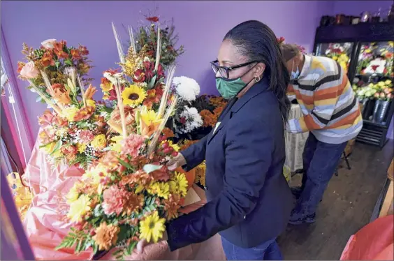  ?? Photos by Will Waldron / Times Union ?? Marie Campbell looks over some of the arrangemen­ts in her flower shop, Blooms By Marie, on Madison Avenue in Albany. The small business has seen unexpected success this year.