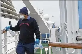  ?? MICHELE SMITH VIA AP ?? A cruise ship worker cleans a railing on the Grand Princess. Scrambling to keep the coronaviru­s at bay, the ship with about 3,500 people aboard was ordered to stay back from the California coast until passengers and crew can be tested.