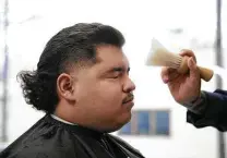  ?? Lisa Krantz / Staff photograph­er ?? Jonne Jasso brushes hair off the face of Cristian Muñiz after his haircut at Pinstripes Classic Barber Shop in San Antonio.