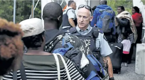  ?? CHARLES KRUPA/THE CANADIAN PRESS ?? An RCMP officer standing in Saint-Bernard-de-Lacolle, Que., on Aug. 7, advises migrants that they are about to illegally cross from Champlain, N.Y., and will be arrested. A spokesman for Public Safety Minister Ralph Goodale says an RCMP questionna­ire...