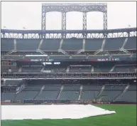  ?? Seth Wenig / Associated Press ?? Members of the Philadelph­ia Phillies staff retrieve some gear during a rain delay before a game between the New York Mets at Citi Field on Thursday. The game was postponed due to rain.