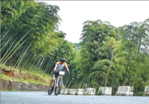  ?? XU YU / XINHUA ?? An 18-kilometer cycling route cuts through Anji’s bamboo forests. Bamboo is able to mitigate the effects of climate change through rapid reforestat­ion.