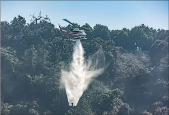  ?? Cory Rubin/The Signal ?? A Cal Fire helicopter drops water on small flare-ups from the Saddleridg­e Fire, near Weldon Canyon in Newhall, on Monday afternoon.