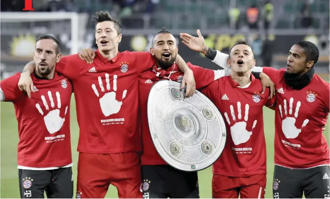  ?? —AFP ?? WOLFSBURG: Bayern’s team celebrates with a mock-trophy becoming the new German champion after the German first division Bundesliga football match between VfL Wolfsburg and Bayern Munich.