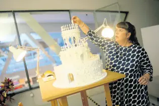  ?? ?? Joana Vasconcelo­s places a human figure on the top tier of a model of her 12 metres high and 15 metres wide ceramic wedding cake.