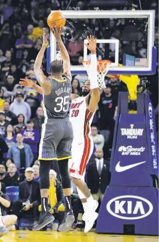  ?? Carlos Avila Gonzalez / The Chronicle ?? The Warriors’ Kevin Durant shoots over Miami’s Justise Winslow to tie the game at 118.