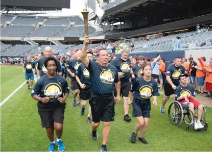  ??  ?? Steve Stelter carries the Special Olympics torch at Soldier Field on Friday before the lighting of the Eternal Flame of Hope.