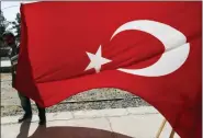  ?? LEFTERIS PITARAKIS - THE ASSOCIATED PRESS ?? A man holds a Turkish flag at the border between Turkey and Syria, in Akcakale, Sanliurfa province, southeaste­rn Turkey, Tuesday. The Turkey - Syria border has became a hot spot as Turkish Vice President Fuat Oktay said Turkey was intent on combatting the threat of Syrian Kurdish fighters across its border in Syria.