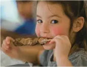  ?? ?? Dimitra Yialamas, 5, of Emmaus, takes another bite out of her pork souvlaki Friday during the Spring Greek Festival at St. Nicholas Greek Orthodox Cathedral in Bethlehem.