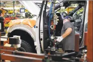  ?? Associated Press ?? A United Auto Workers member installs the front doors on a 2018 Ford F-150 truck being assembled at the Ford Rouge assembly plant in Dearborn, Mich. American industry is generally healthy, but respondent­s to a new survey suggested that trade disputes are taking a toll.
