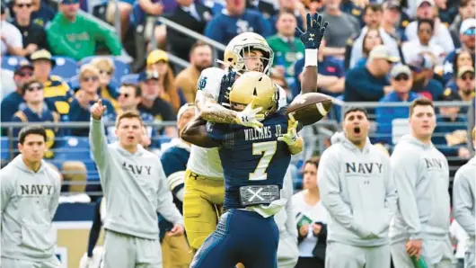  ?? TERRANCE WILLIAMS/AP ?? Notre Dame wide receiver Braden Lenzy catches the ball by pinning it against the back of Navy cornerback Mbiti Williams Jr. to score a touchdown during the first half of Saturday’s game at M&T Bank Stadium. The Fighting Irish took a 35-13 lead into halftime, but the Mids responded with a late rally.