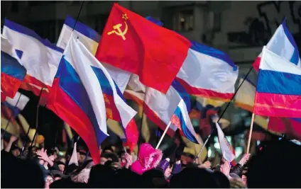  ?? VADIM GHIRDA/ THE ASSOCIATED PRESS ?? Pro- Russian people celebrate in Lenin Square, in Simferopol, Ukraine, on Sunday. Fireworks exploded and Russian flags fluttered above jubilant crowds Sunday after residents in Crimea voted overwhelmi­ngly to secede from Ukraine and join Russia.