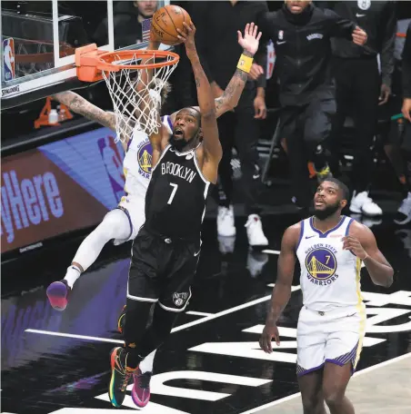  ?? Sarah Stier / Getty Images ?? Kevin Durant of the Nets dunks in front of the Warriors’ Kelly Oubre Jr. and Eric Paschall ( 7) at Barclays Center in Brooklyn.