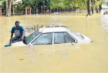  ?? ARIF KARTONO/GETTY-AFP ?? Waiting for help: A man waits for a rescue team Monday in Shah Alam, a city in Malaysia’s Selangor state that saw weekend floods. Prime Minister Sabri Yaakob said Monday that the amount of rain that fell Saturday on Selangor “would usually fall in one month.” Over 10,000 people have been evacuated from the area around the capital of Kuala Lumpur.