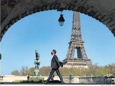  ?? IAN LANGSDON / EFE ?? Un peatón con mascarilla camina por el puente Bir Hakeim, cercano a la Torre Eiffel, el miércoles en París.
