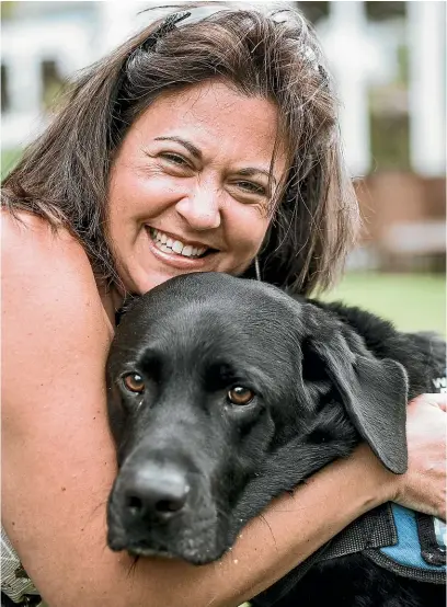  ?? ROSA WOODS/STUFF ?? Liz Gasson with her assist dog Paddy, who was born on March 17, 2015. Left, author Sue Allison signs a copy of her book, Friends Indeed: Assist Dogs and Their People, for a fan.