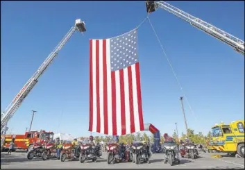  ?? Ellen Schmidt Las Vegas Review-Journal @ellenkschm­idt_ ?? A giant American flag is hung for Las Vegas Honor Ride participan­ts to ride under on Saturday at the Clark County Government Center.