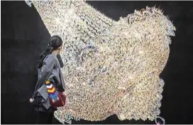  ??  ?? A visitor looks at a piece of a series by South Korean artist Kyungah Ham entitled Chandelier­s For Five Cities.