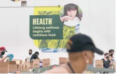  ?? JACQUELYN MARTIN/AP ?? Volunteers pack boxes of food for distributi­on last week at The Capital Area Food Bank in Washington.