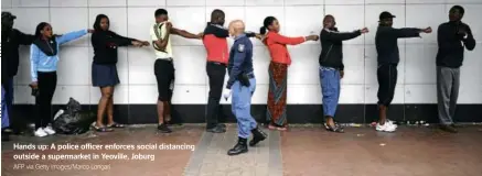  ?? AFP via Getty Images/Marco Longari ?? Hands up: A police officer enforces social distancing outside a supermarke­t in Yeoville, Joburg