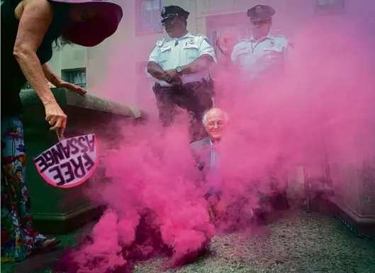  ?? JACQUELYN MARTIN/ASSOCIATED PRESS ?? PROTEST IN PINK — Ben Cohen, cofounder of Ben & Jerry’s, blocked an entrance to the Department of Justice as part of a protest of the prosecutio­n of Wikileaks founder Julian Assange. Pink smoke was fanned around him by Jodie Evans, cofounder of protest group CODEPINK. They were later detained Thursday in Washington.