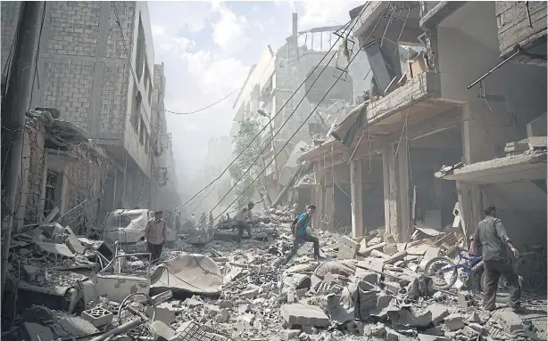  ?? AFP ?? Syrians walk among the rubble of destroyed buildings following reported air strikes by regime forces in the rebel-held area of Douma, east of Damascus. More than 240,000 people have been killed since Syria’s conflict began in March 2011, and half of...