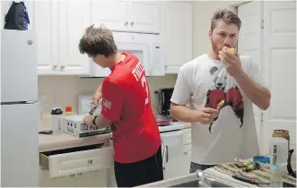  ??  ?? Matt Pare of the single-A Augusta GreenJacke­ts, left, opens a box of eggs in the kitchen as teammate Adam Sonabend eats an apple with peanut butter during breakfast in an apartment they share with other teammates.