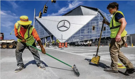  ?? JOHN SPINK / JSPINK@AJC.COM ?? FINALPREPA­RATIONS: Womack Caldwell (left) and Tommy Stanhopewo­rk on last-minute paving and striping details Friday outsideMer­cedes-Benz Stadium. The $1.5 billion stadiumwil­l offifficia­lly open tonight as the Falcons host the Arizona Cardinals in an...