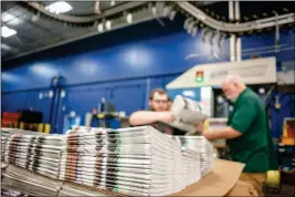  ?? ANGELA MAJOR/THE JANESVILLE GAZETTE VIA AP ?? IN THIS APRIL 11 PHOTO, production workers stack newspapers onto a cart at the Janesville Gazette Printing & Distributi­on plant in Janesville, Wis. Newspaper publishers across the U.S. already strapped by years of declining revenue say they’re dealing...