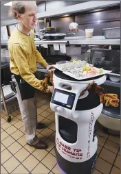  ?? ?? Matthew Woestman places meals on a robot waiter.