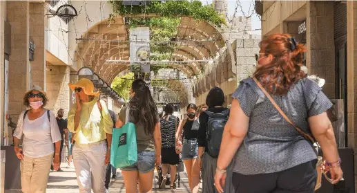  ?? (Marc Israel Sellem/The Jerusalem Post) ?? MASKED AND unmasked people walk along Jerusalem’s Mamilla pedestrian mall yesterday.