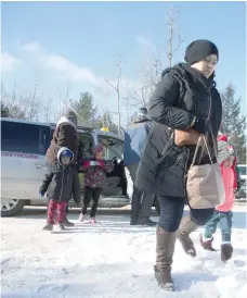  ?? — Reuters ?? A family that claimed to be from Sudan leaves a taxi to walk across the US-Canada border into Hemmingfor­d, Canada, from Champlain in New York, on Saturday.