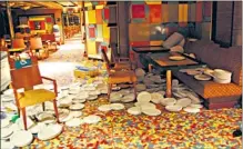  ??  ?? Crockery is scattered in a deserted dining area after the ship hit rocks, and passengers pose for a photograph on the Costa Concordia before the seriousnes­s of the disaster unfolded. A child is helped into a life jacket