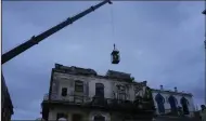  ?? (AP/Ramon Espinosa) ?? A crane lifts firefighte­rs in a cage toward a building in search of survivors after it partially collapsed on Wednesday in Havana, Cuba.