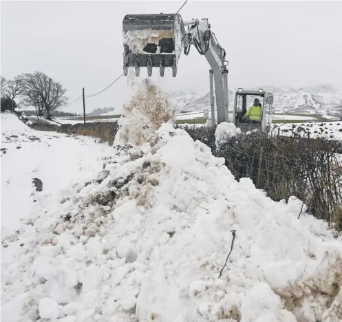  ??  ?? 0 A man clears the B818 with a digger in Fintry as police advised motorists to drive with caution while weather warnings persist