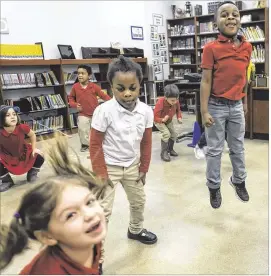  ?? RODOLFO GONZALEZ / AMERICAN-STATESMAN ?? Cali Castro (from left), Mikella Okyere and Ellis King exercise last week in a wellness class taught by Lindsey Simmons at the Meridian charter school in Williamson County. Round Rock schools have lost 700 students to Meridian.