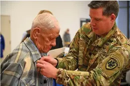  ?? Staff photo by Hunt Mercier ?? ■ Seth Olmstead pins Army veteran Eugene Kahanek on Thursday at the Texarkana Chamber of Commerce veterans luncheon at Texas A&M University-Texarkana.