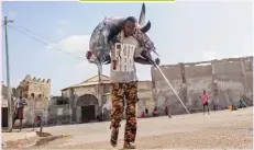  ??  ?? MOHAMED ABDIWAHAB/AFP/GETTY IMAGES A fisherman carries a sailfish to Hamarweyne market, near the port, Mogadishu, Somalia.