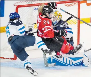  ?? — THE CANADIAN PRESS ?? Canada’s Nathalie Spooner (24) is upended by Finland’s Jenni Hiirikoski (6) in front of Finnish goalie Meeri Raisanen during first-period action at the women’s world hockey championsh­ips Thursday in Kamloops.