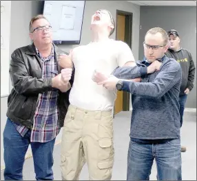  ?? Keith Bryant/The Weekly Vista ?? Bella Vista police Cpl. Rodney Deason, left, helps to hold officer Chase Henry, along with officer Dillon Pruitt while officer Luke Henson, background, applies current with a Taser to demonstrat­e the electric weapon.