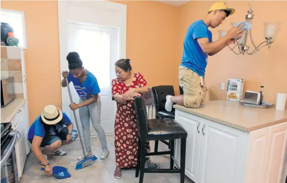  ?? JOHN MAHONEY/ THE GAZETTE ?? Ayesha Ahmed watches as Barbara Lazcano holds the dust pan for Jennika Fletcher and Tae Yeoung Jung dusts the kitchen light fixture at her home in N.D.G. on Sunday.