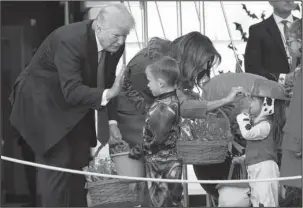  ?? The Associated Press ?? NO TRICKS: President Donald Trump and first lady Melania Trump hand out treats as they welcome children from the Washington area and children of military families to trick-or-treat celebratin­g Halloween at the South Lawn of the White House in...