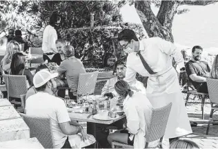  ?? New York Times file photo ?? Restaurant patrons dine outdoors in Miami Beach. The U.S. is particular­ly important to the world economy because it has long spent more than it makes or sells, spreading dollars globally.